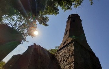 Ruiny w Karwowie. Widok na wieżę kościelną oraz słońce za drzewem