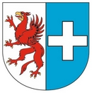 Herb Gminy Kołbaskowo ukazujący czerwonego gryfa ba białym tle oraz biały krzyż na błękitnym tle. 